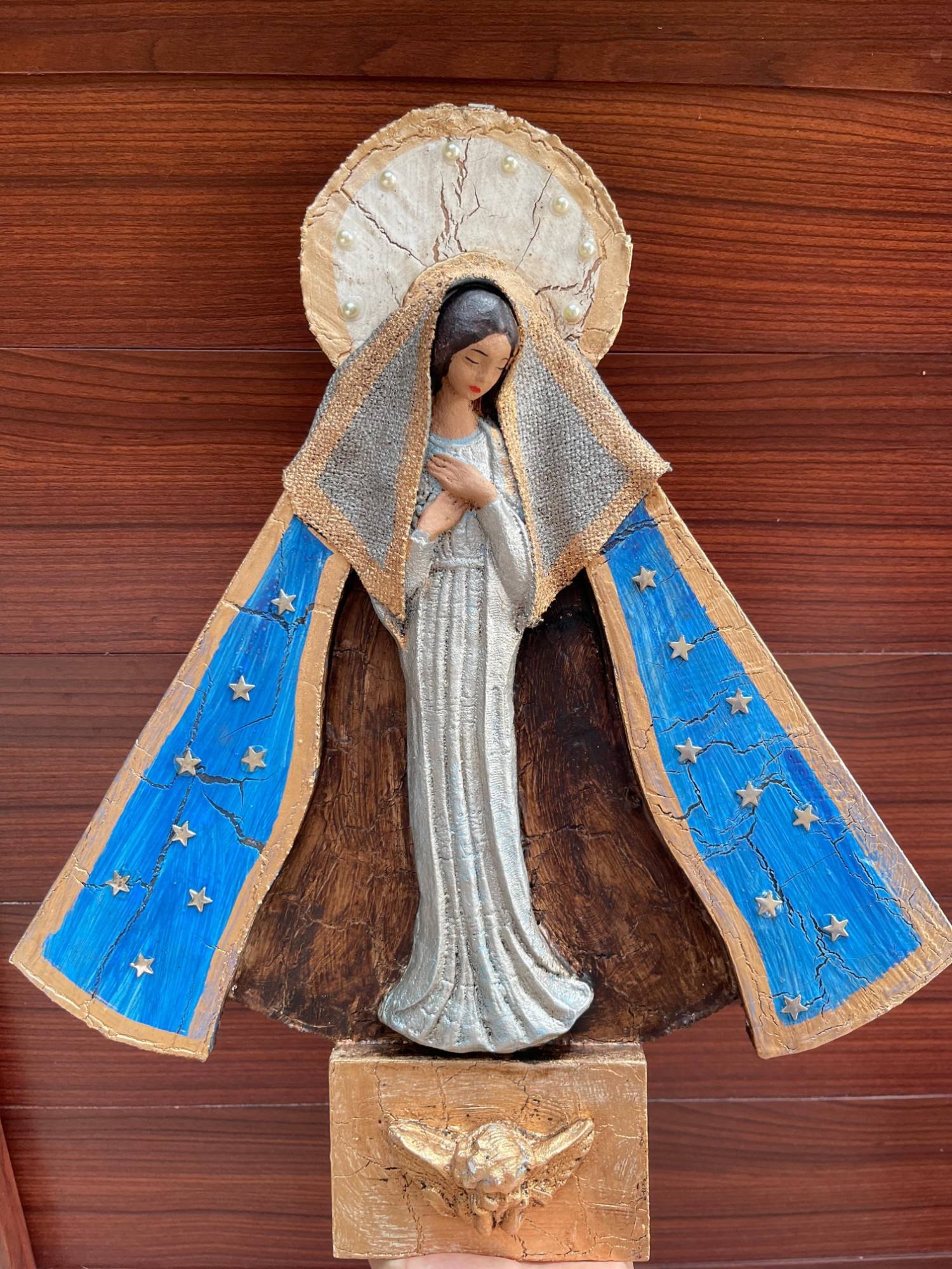 Virgen de madera azul colgada sobre muro de madera